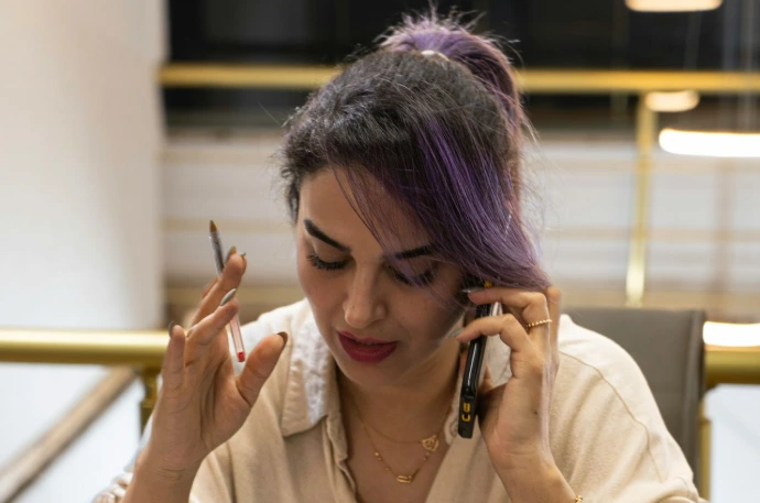 Woman with purple hair talking on phone at desk.
